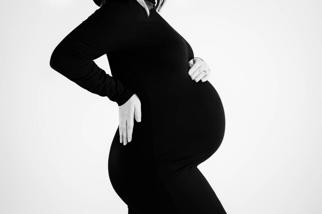 How To Feel Your Best During Pregnancy 8 Close-Up Black And White Maternity Photograph Highlighting Baby Bump And Fitted Maternity Styling In Dallas Studio.