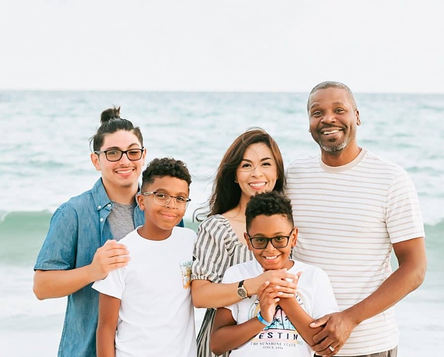 A family smiling for a photo on the beach.