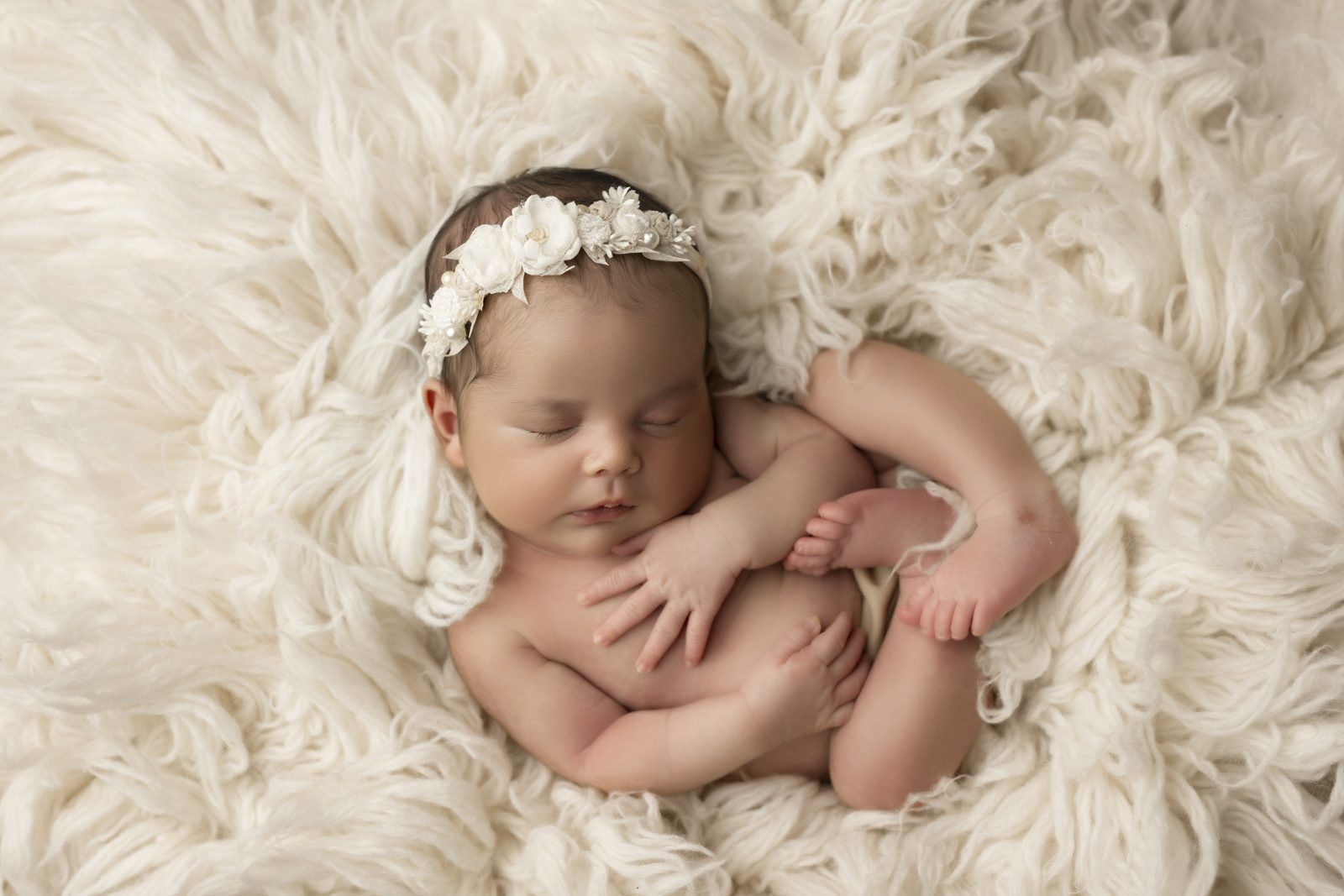 A newborn girl laying on a fluffy blanket.
