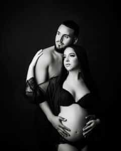 A Monochrome, High-Contrast Image Of A Pregnant Couple With Husband Embracing From Behind During An Artistic Maternity Photo Shoot, Which Is A Dream Maternity Shoot For Many Dallas Moms To Be