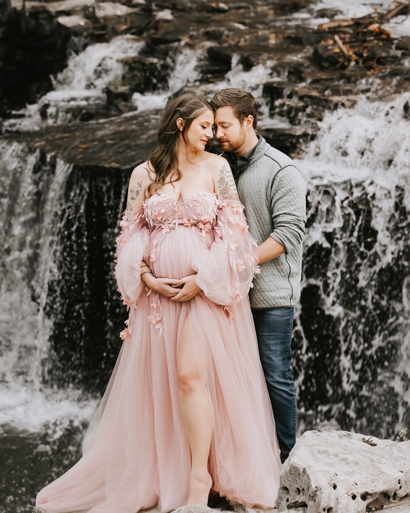 Pregnant Woman In A Pink Dress Stand By A Waterfall For Maternity Photos Dallas
