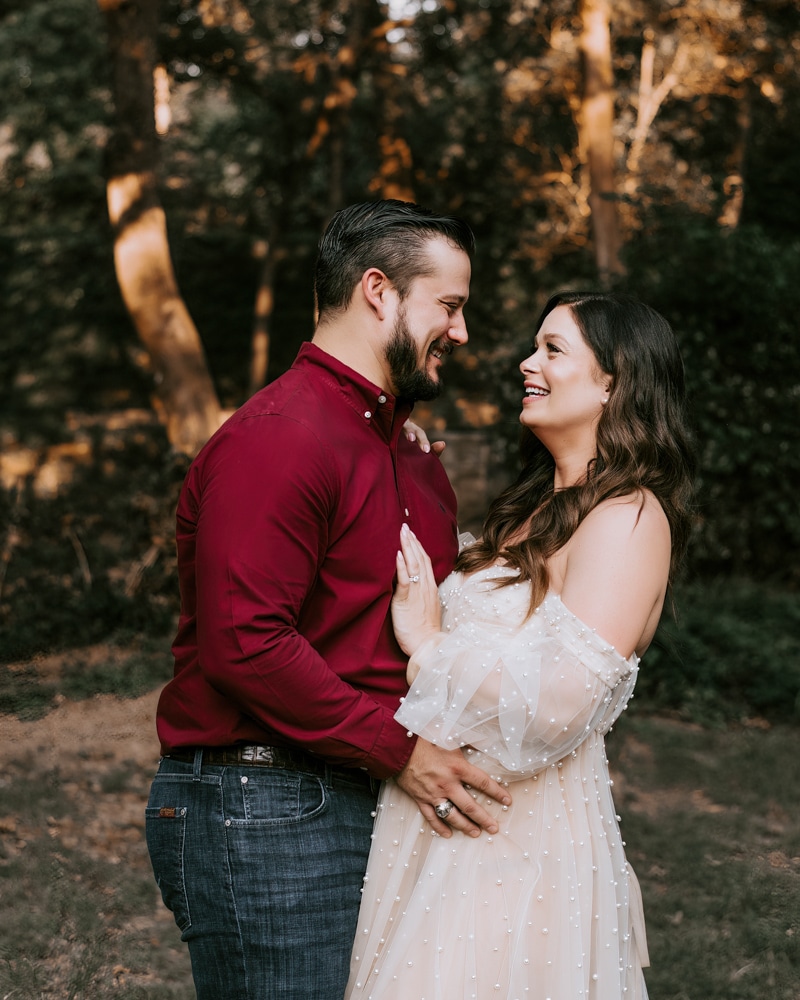 Pregnant Couple Embraced For Maternity Photos Near Trees