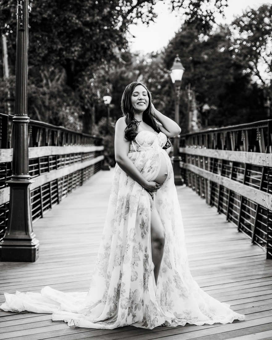 Pregnant Woman In A Flowing Floral Dress Smiling For Dfw Maternity Photographer