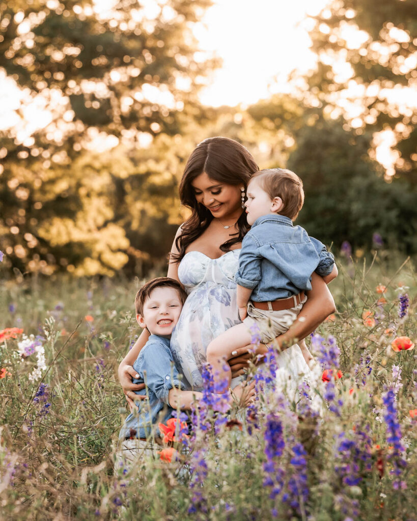 Mother With Children During Outdoor Maternity Photography Session In A Texas Wildflower Field