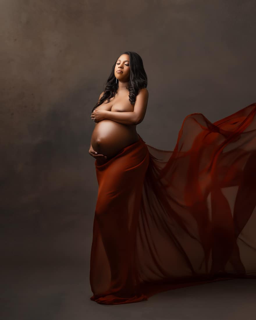 Pregnant Woman Standing With Eyes Closed Wrapped In Flowing Fabric For Maternity Photo Shoot Dallas