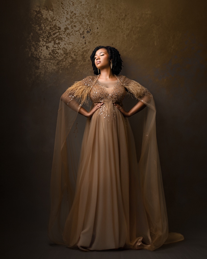 pregnant woman in gold gown stands for maternity photos posing for dallas maternity photographer