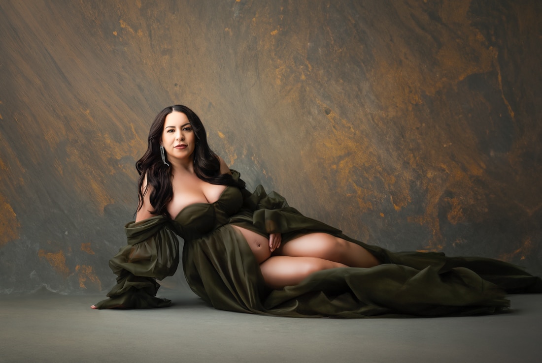 pregnant woman in an elegant green gown posing during a fine art maternity photography session in a Dallas studio