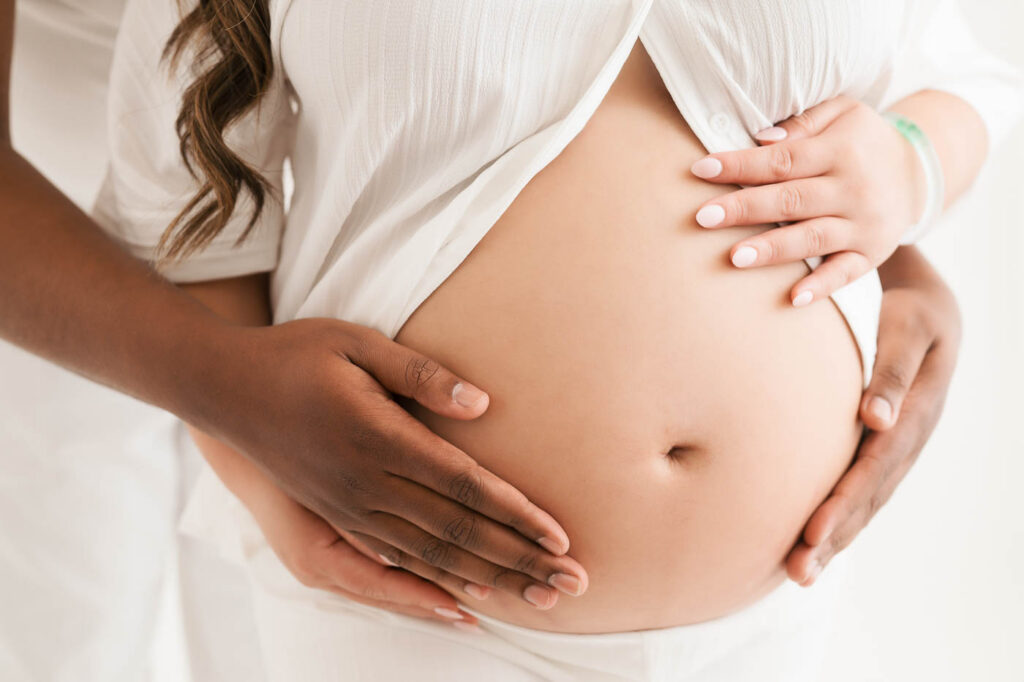Close-Up Maternity Photograph Highlighting Baby Bump And Hands During Pregnancy Session