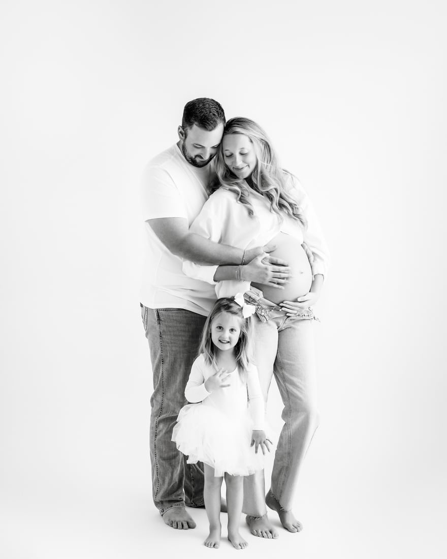 Pregnant Couple Stands Together Smiling At Daughter For Maternity Photos With Dallas Maternity Photographer 