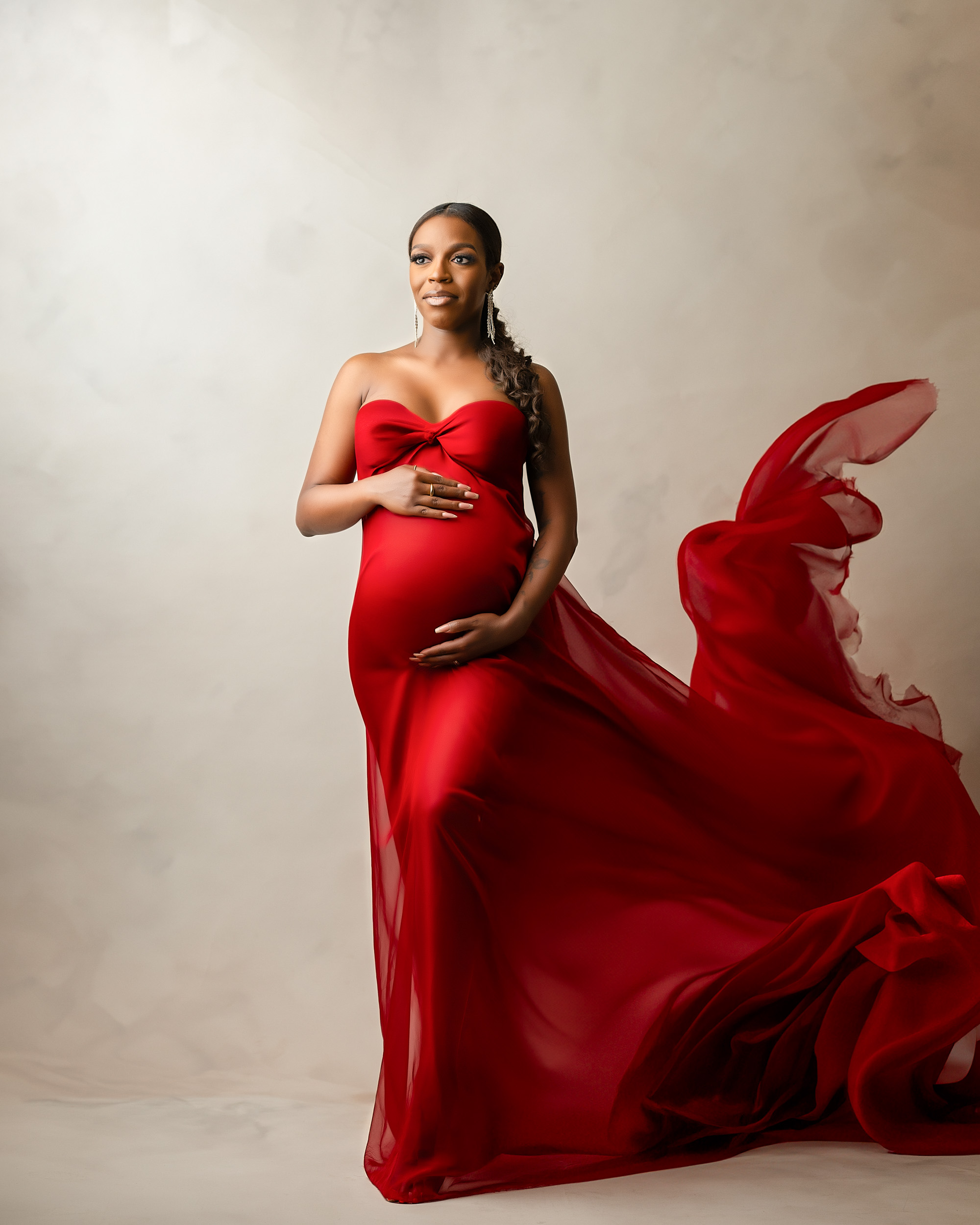 pregnant woman in flowing red gown during a fine art maternity photography session in Dallas studio by Lily Hayes