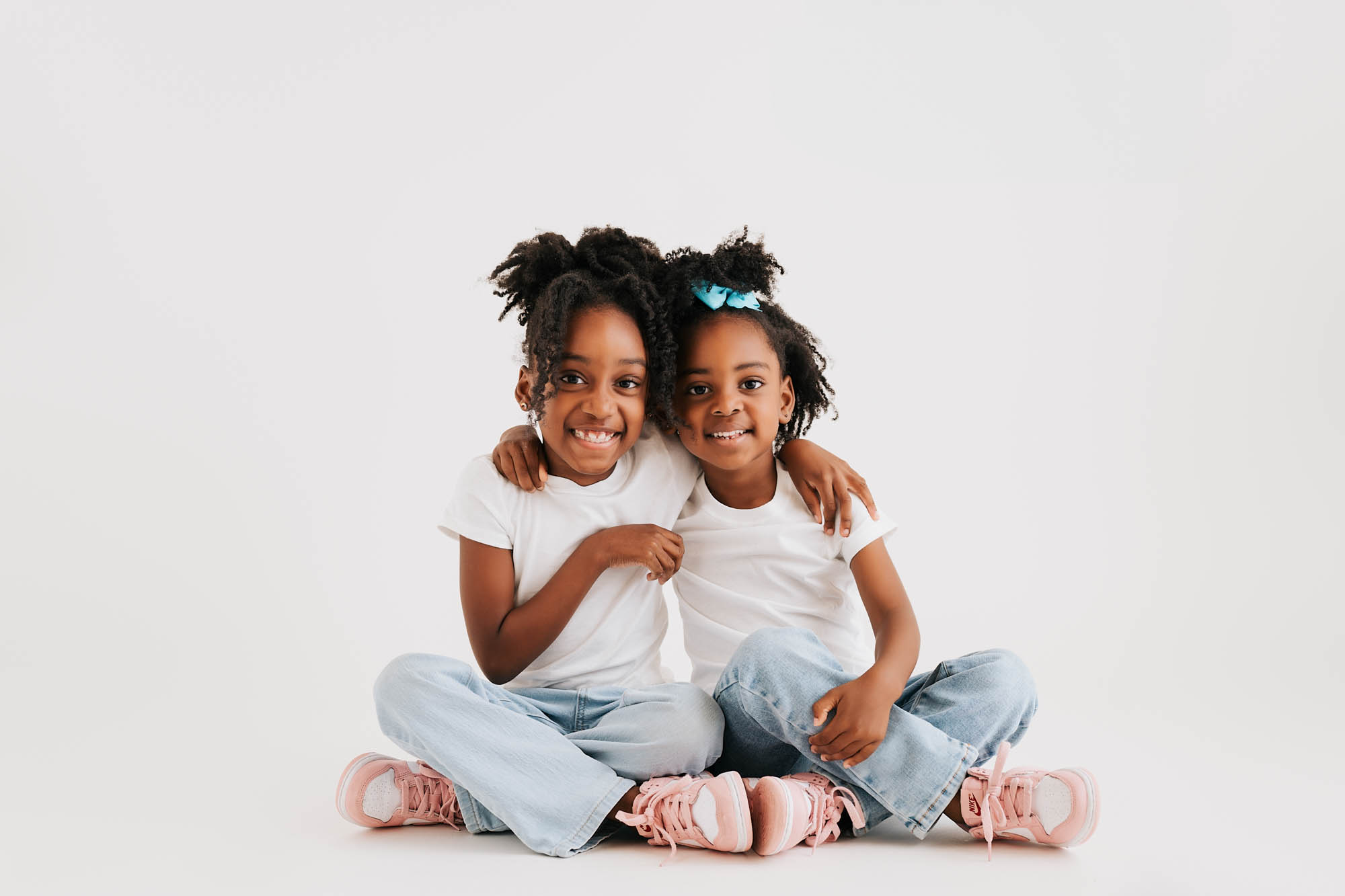 Two Sisters Hugging During A Dallas Maternity Photography Session In A Lifestyle Studio