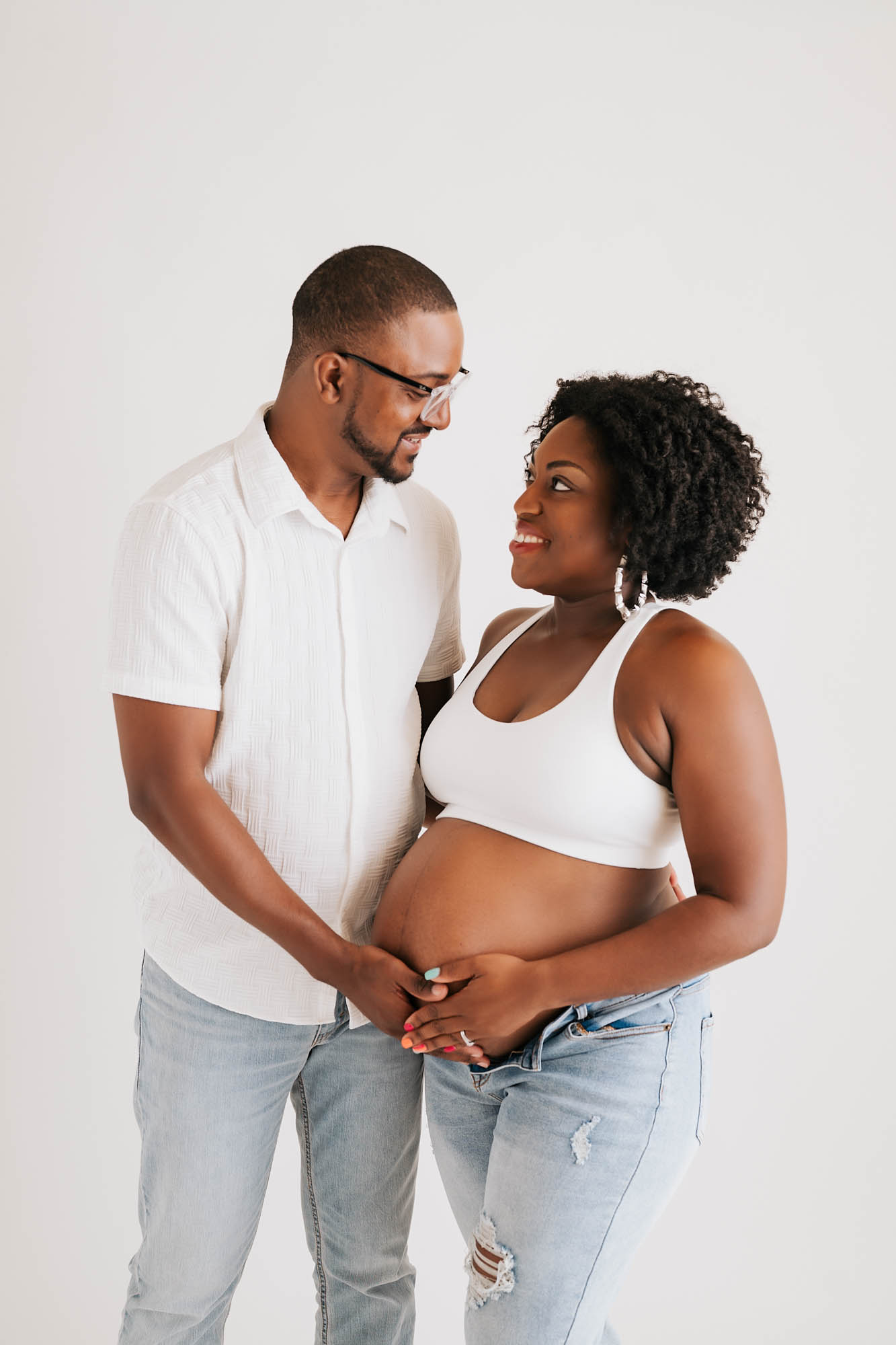 Happy Expecting Couple Holding Baby Bump Together During Intimate Maternity Photoshoot In Dallas