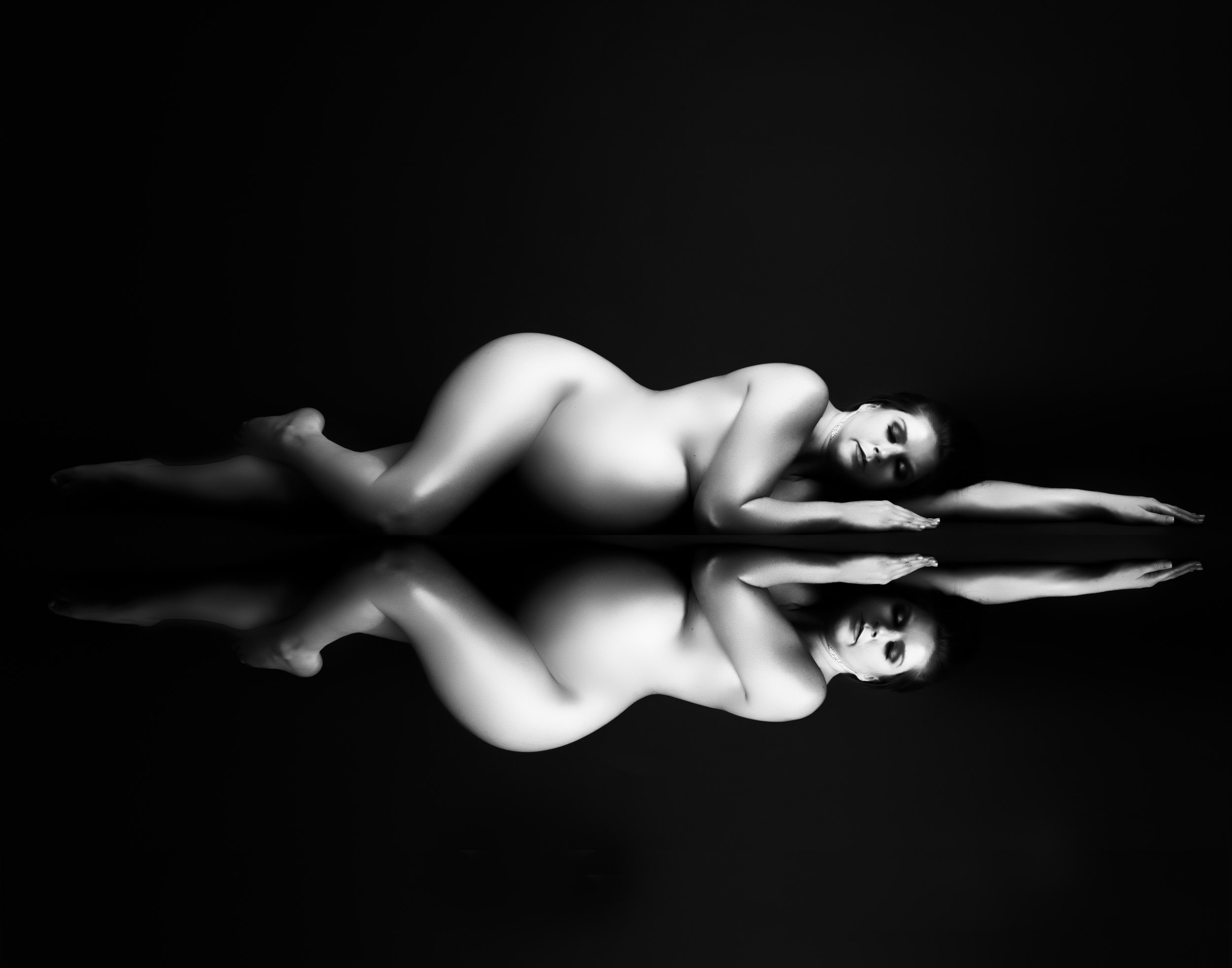 Rtistic Black And White Maternity Portrait Of A Pregnant Woman Lying Down With Her Reflection, Photographed By Dallas Maternity Photographer