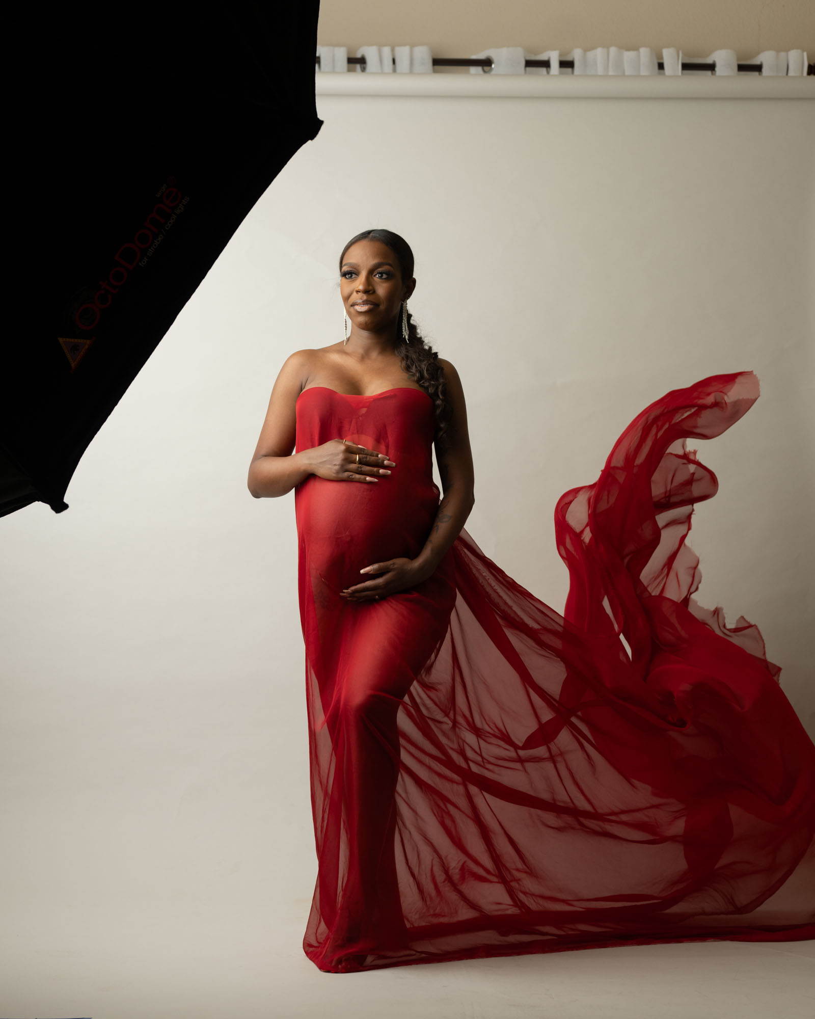 Pregnant woman in flowing red gown during Dallas maternity studio photoshoot