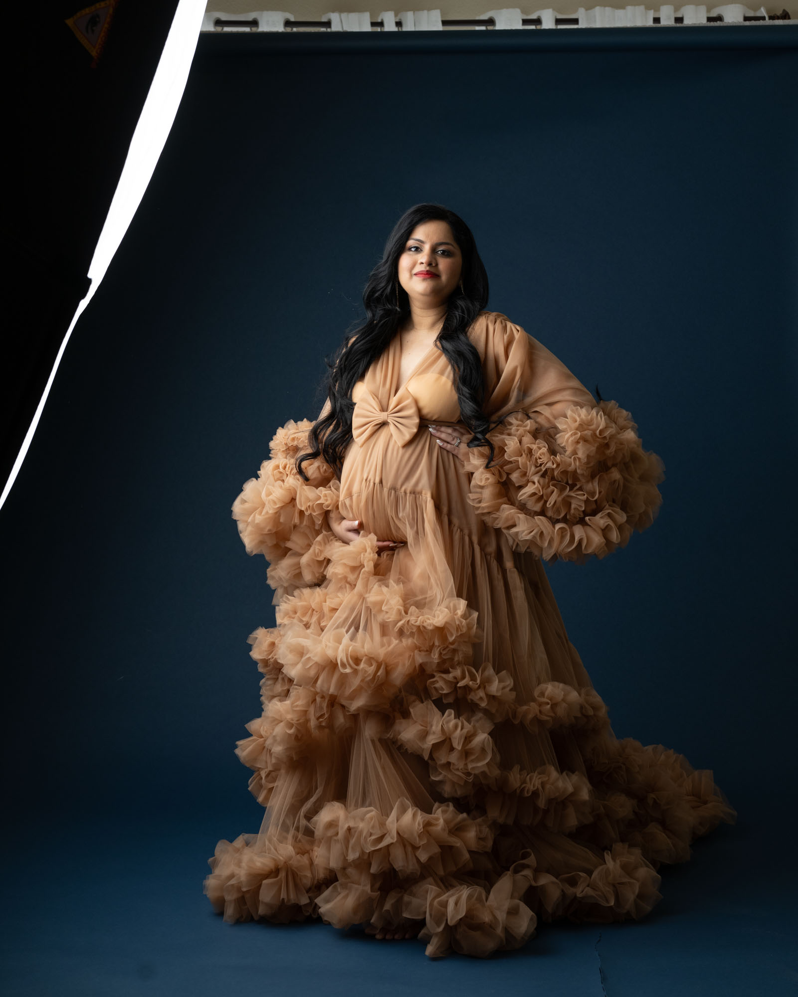 Pregnant woman in elegant tulle gown during Dallas studio maternity photoshoot