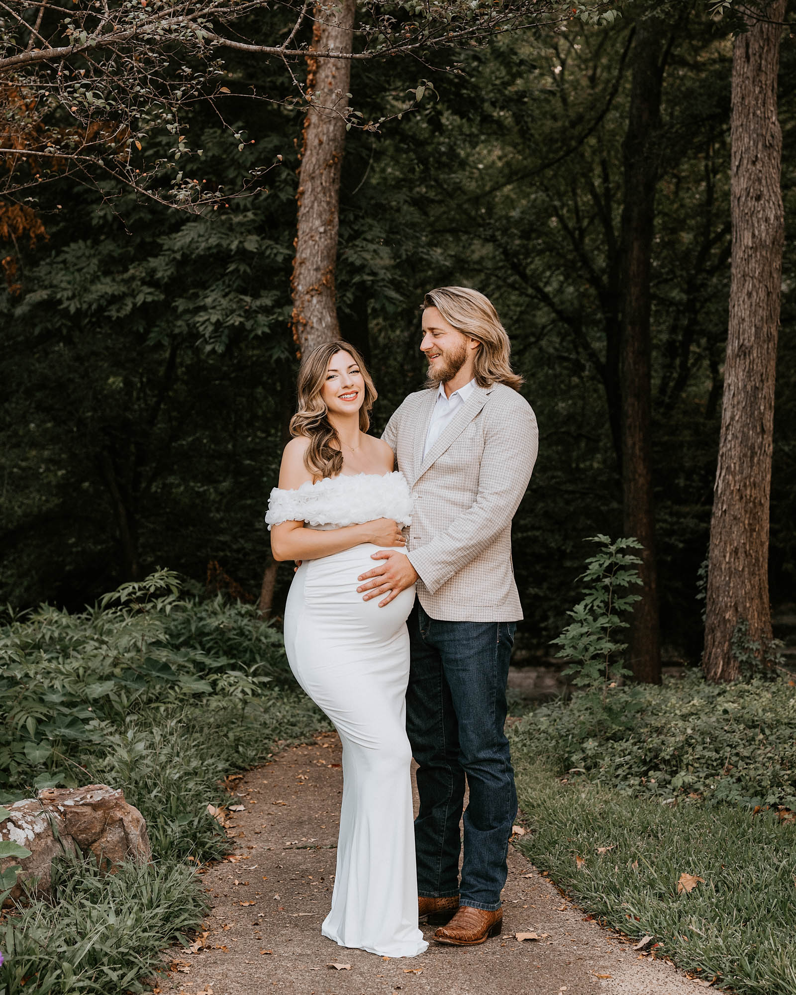Couple maternity photography in Dallas with husband embracing wife in fitted white dress