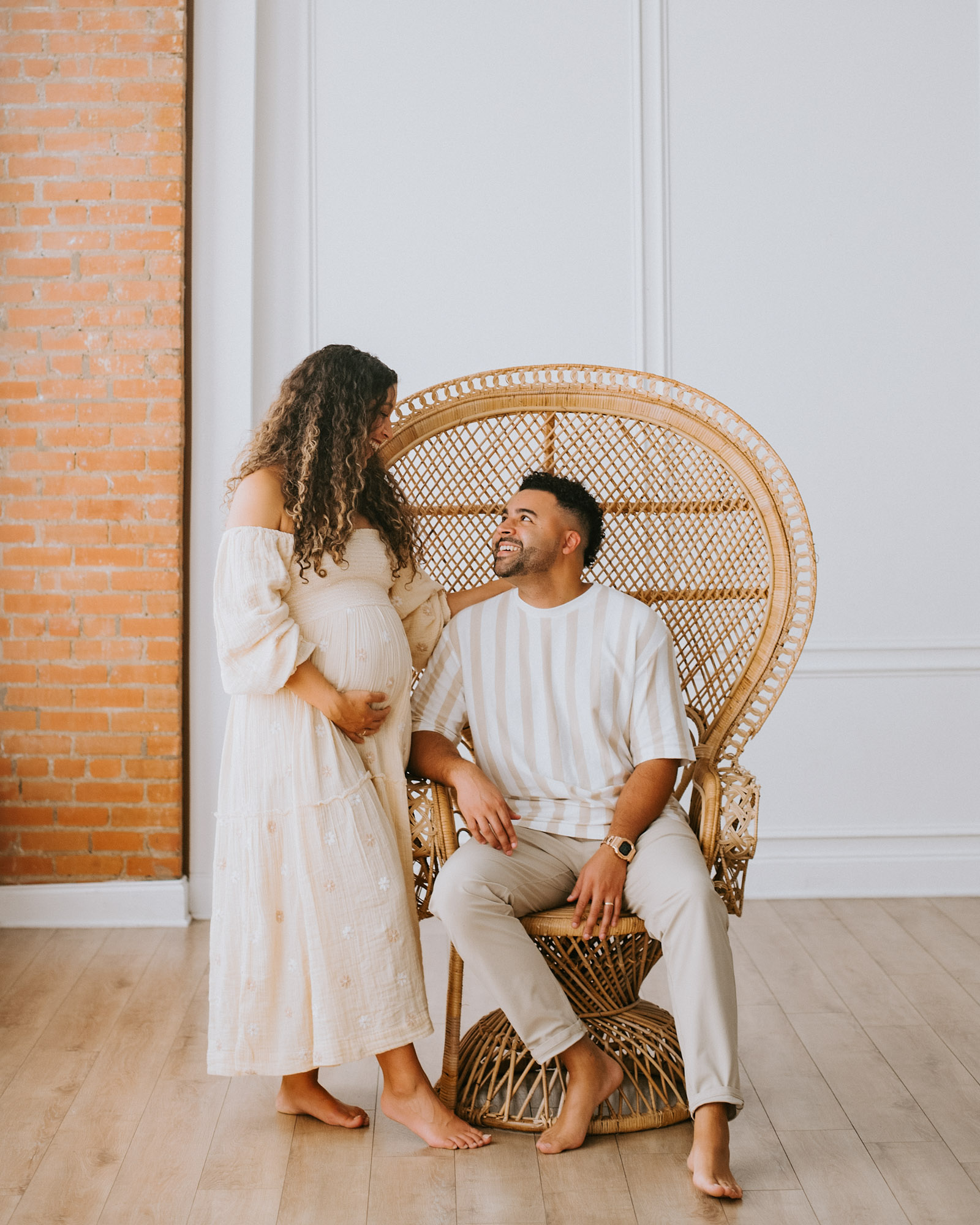 Husband Smiling At Wife During Maternity Session In Dallas Studio Chair