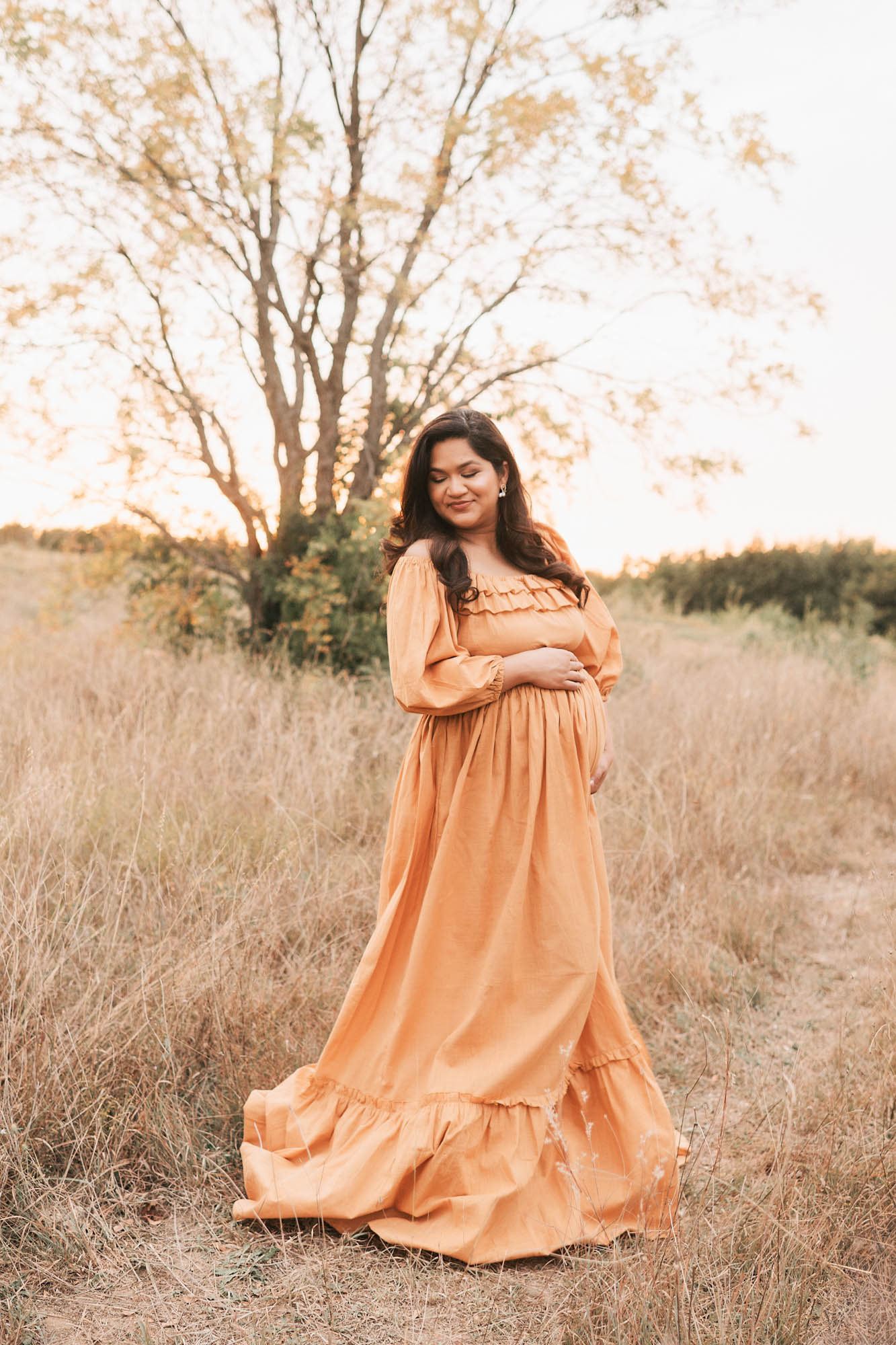 Expecting Mom Standing In A Golden Field At Sunset During An Outdoor Maternity Session In Dallas