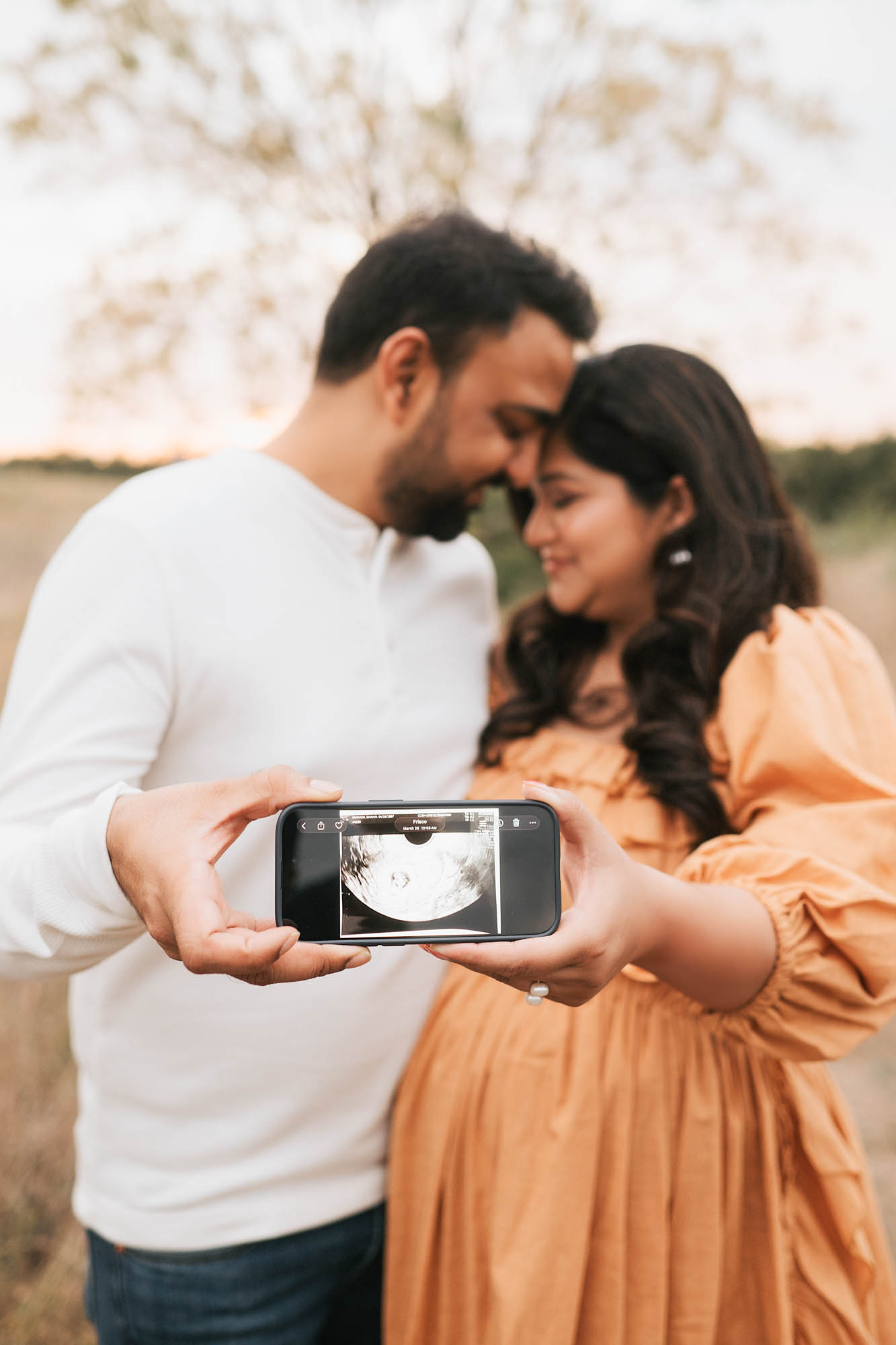 Expecting Couple Holding A Phone Displaying Their Baby’s Ultrasound During A Dallas Maternity Photoshoot