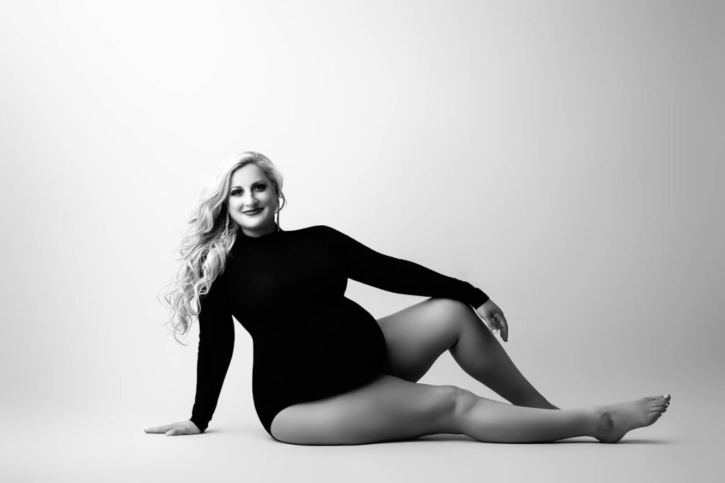 Studio Maternity Portrait Of A Pregnant Woman Seated On The Floor In A Black Bodysuit, Photographed In Dallas By Lily Hayes Photography
