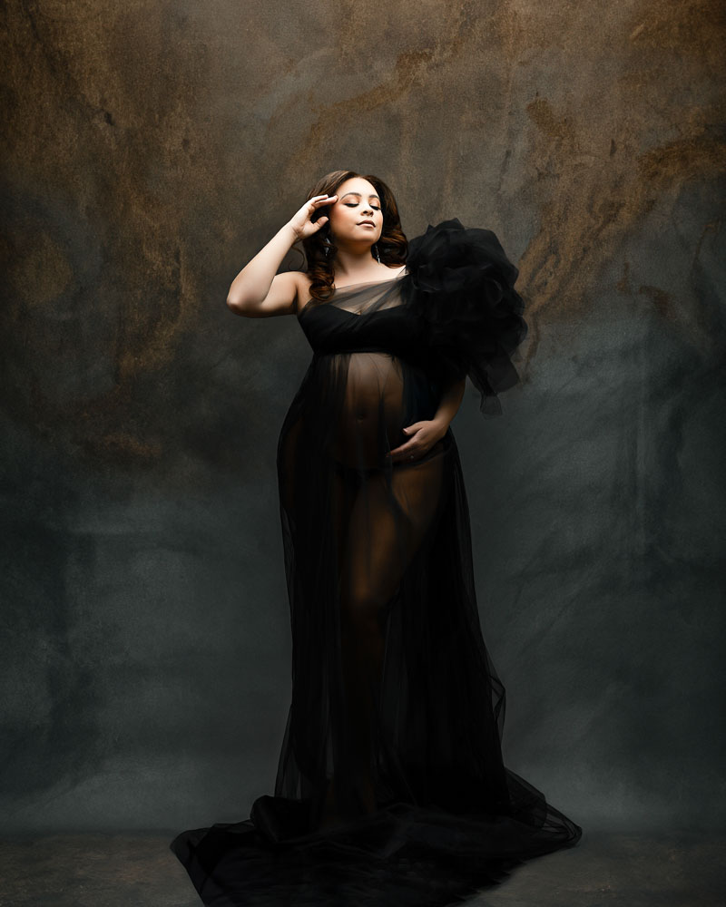 Dallas maternity photographer captures fine art portrait of expecting mother in black gown against textured studio backdrop