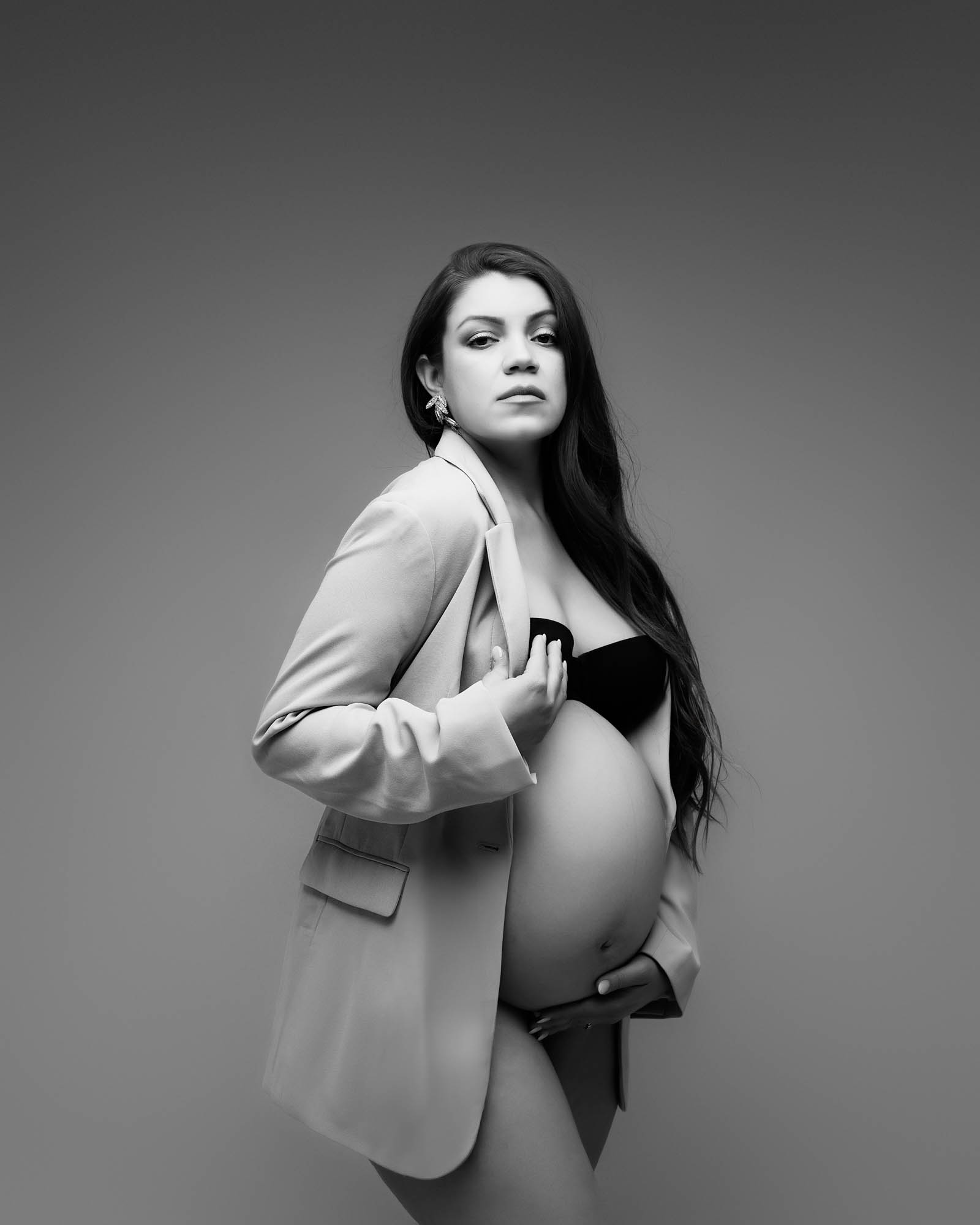 Elegant black and white maternity portrait of an expecting mother wearing a blazer, photographed in a Dallas maternity photography studio
