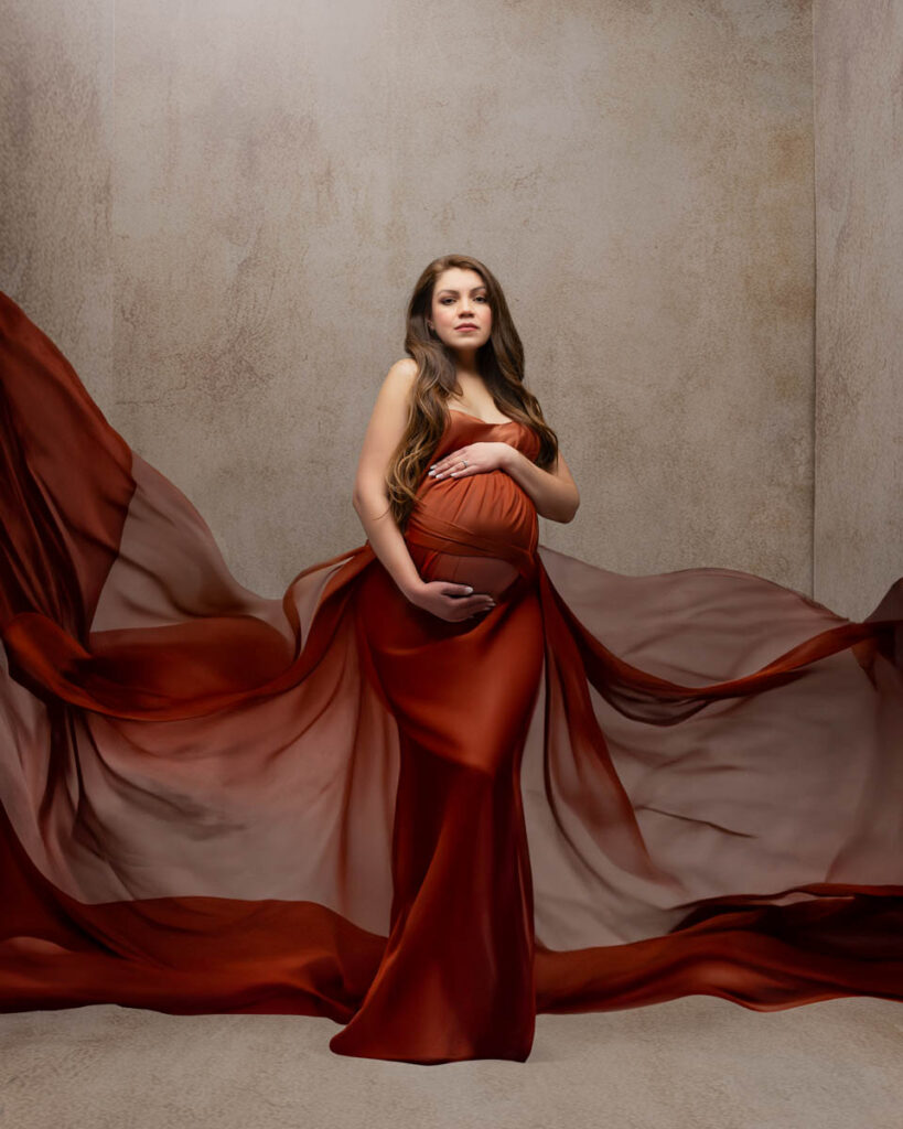 Dallas Maternity Photography Portrait Of Pregnant Woman In Red Gown With Flowing Fabric In Studio