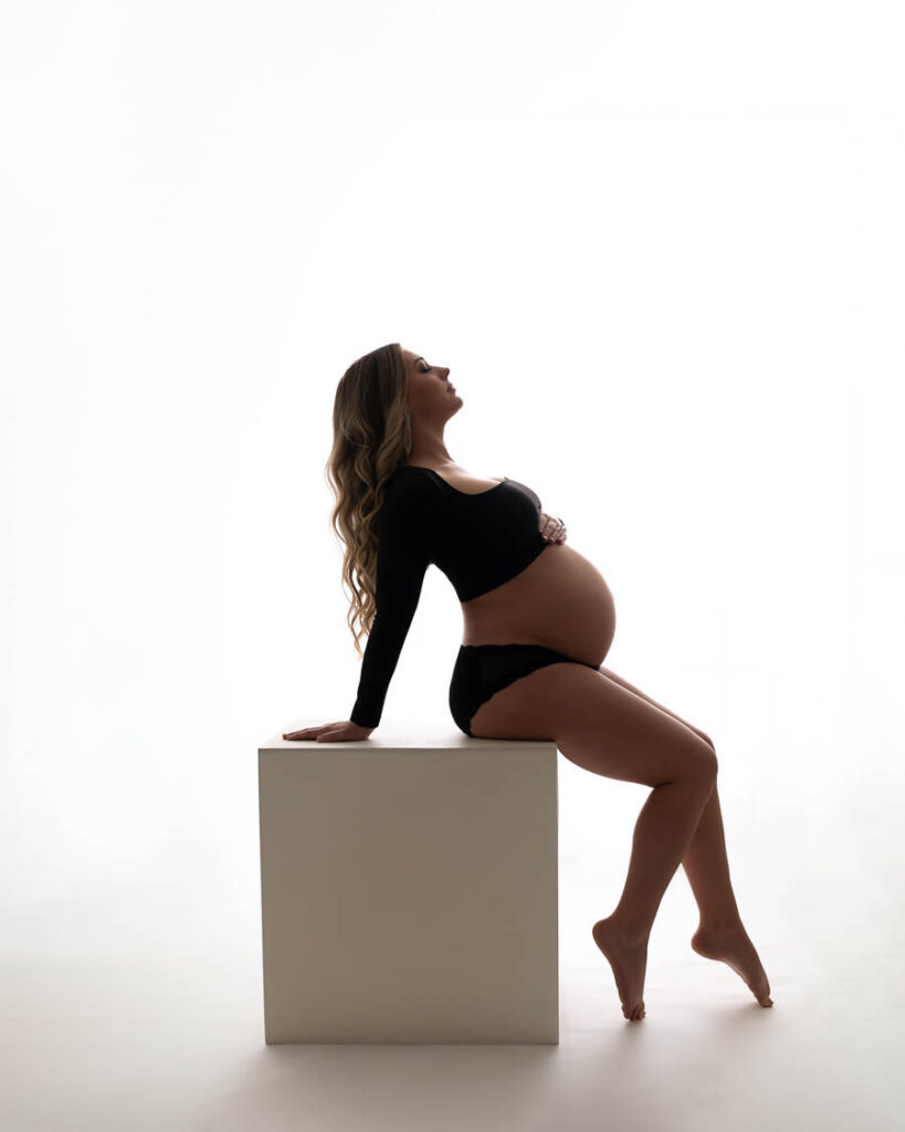 How Luxury Maternity Photography Creates Timeless Artwork 10 Dfw Maternity Photographer Captures Mother-To-Be Posing On A White Cube During A Fine Art Maternity Portrait Session In Dallas.