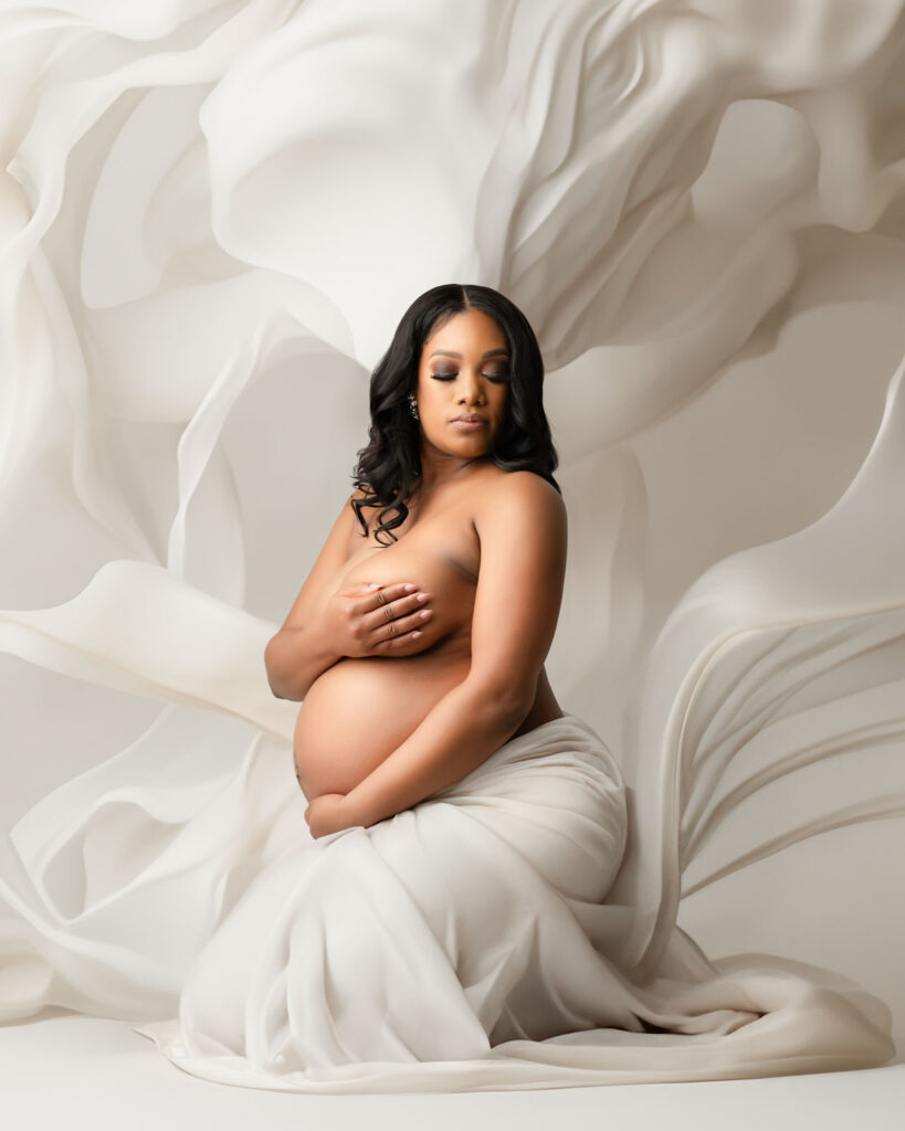 Fine Art Maternity Photoshoot In Dallas Featuring An Expectant Mother Posed With Flowing White Fabric In A Luxury Studio Portrait.