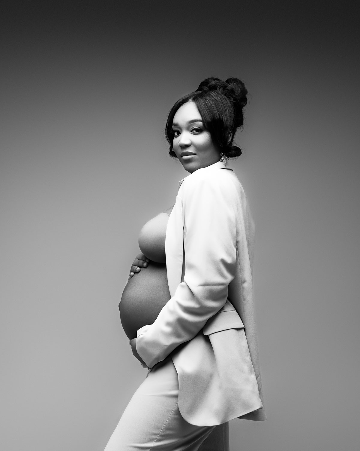 Dallas maternity photographer capturing elegant editorial pregnancy portrait in white suit studio session