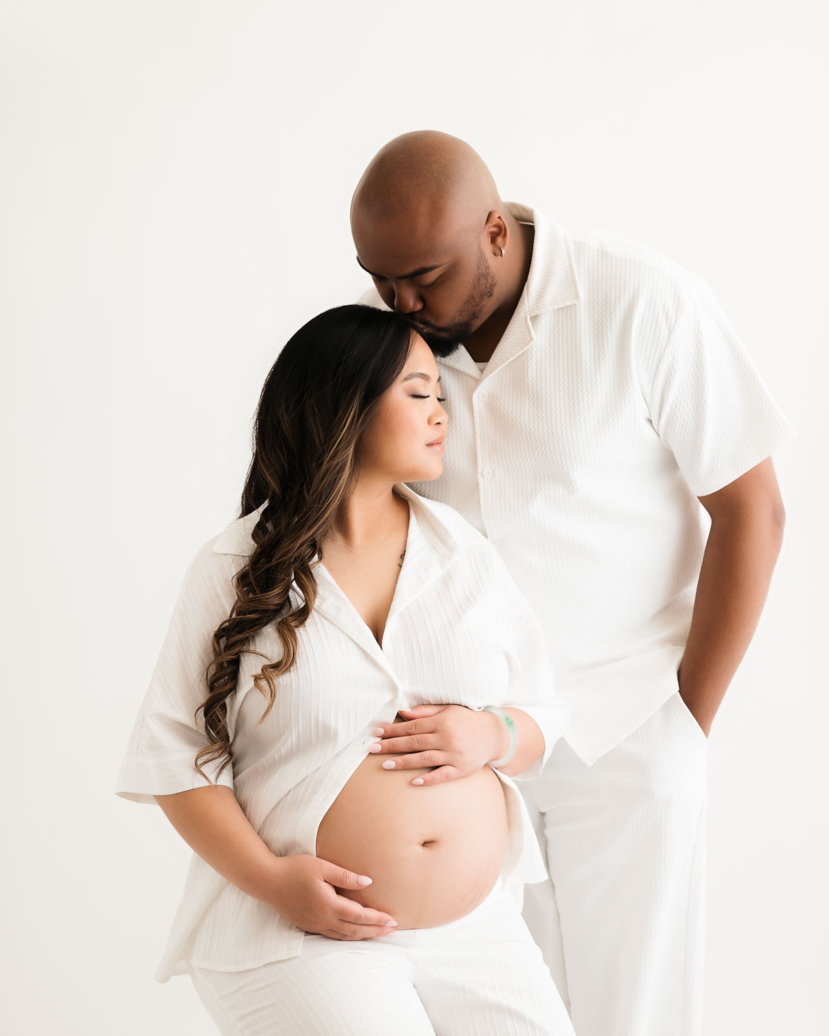 Dallas maternity photographer capturing elegant pregnancy couple portrait in bright white studio