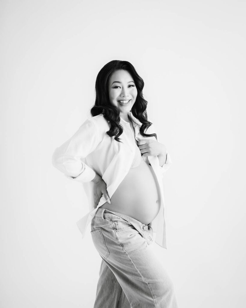 Studio Maternity Portrait In Black And White Featuring An Expecting Mother In Casual Wardrobe Styling.