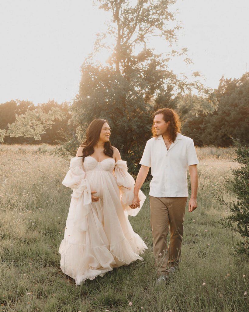 Expectant Couple Walking Together During An Outdoor Maternity Session In Dallas At Sunset.