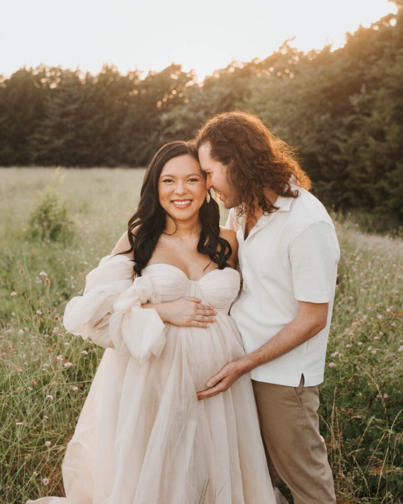 Couple Smiling Together During An Elegant Outdoor Maternity Session In Dallas.