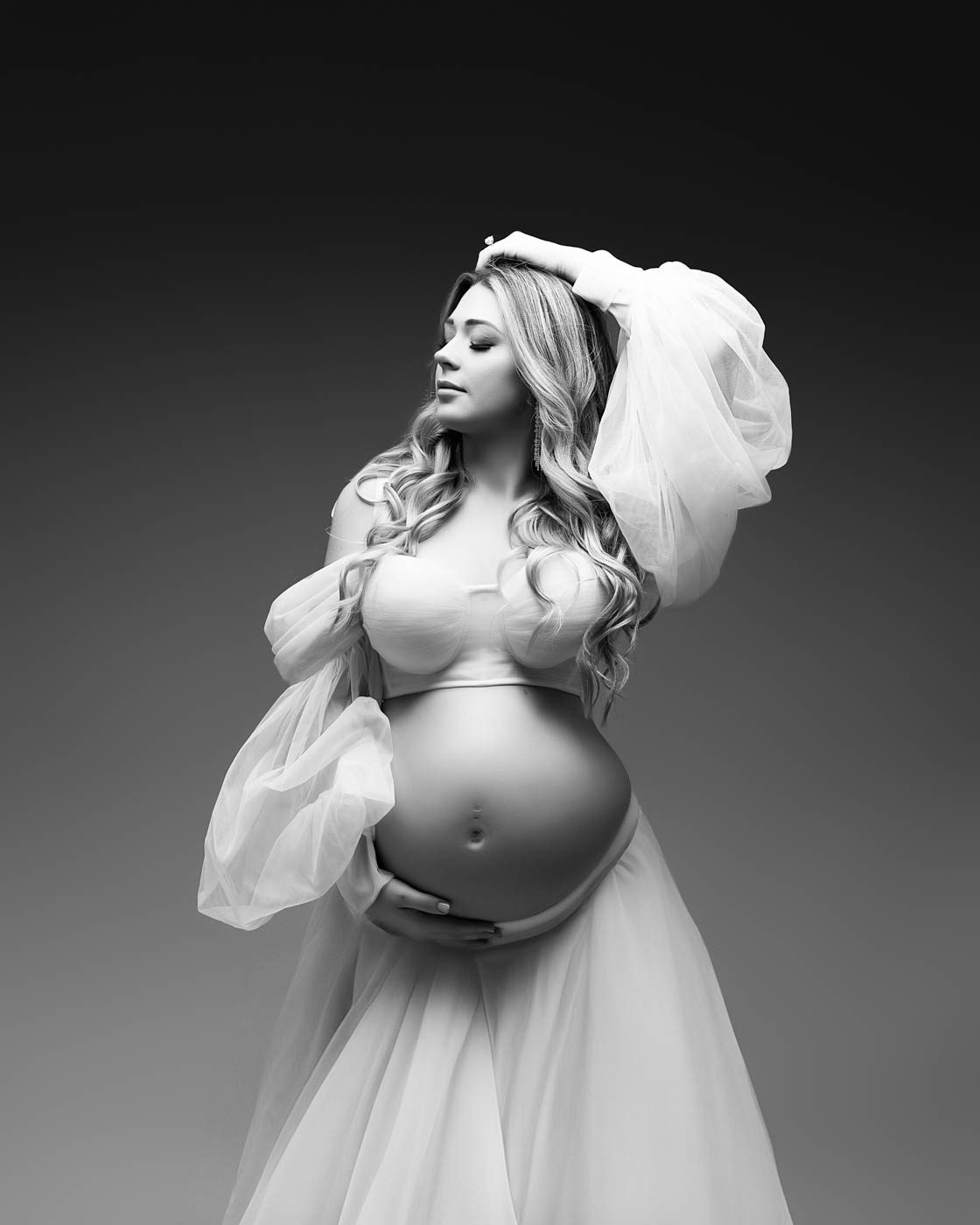 Maternity photography Dallas portrait of a pregnant woman styled in sheer fabric with her belly exposed