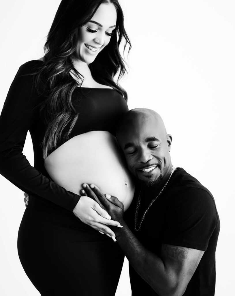 Dallas Maternity Couple Portrait With The Father Leaning Beside The Mother’s Baby Bump