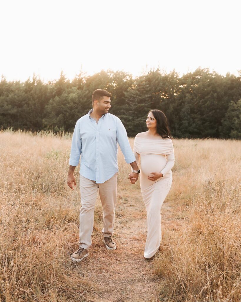 Dallas Pregnancy Photographer Captures An Expecting Couple Walking Together During An Outdoor Summer Maternity Session.