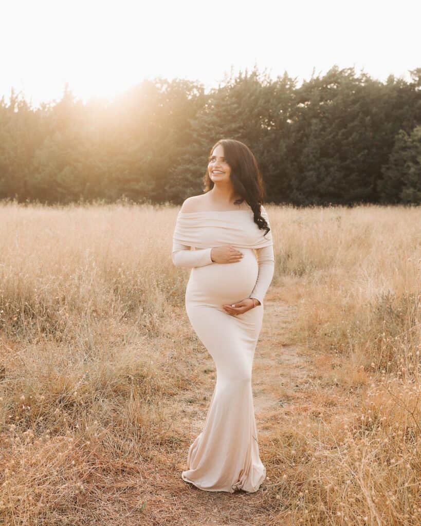 Expecting Mother In A Fitted Neutral Dress During Outdoor Maternity Photography In Dallas On A Summer Evening.